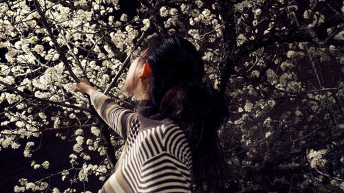 Side view of young woman holding branch