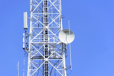 Low angle view of communications tower against clear blue sky