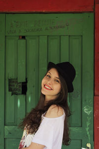 Portrait of young woman standing against wall