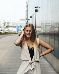 Portrait of smiling young woman standing against the wall