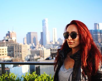 Redhead woman wearing sunglasses and leather jacket in city