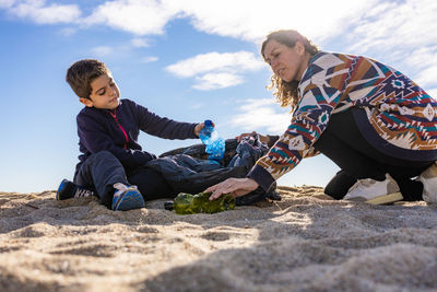 Mother and son picking plastic and garbage on the beach