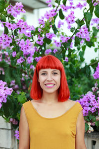 Portrait of smiling woman standing against pink flowering plants