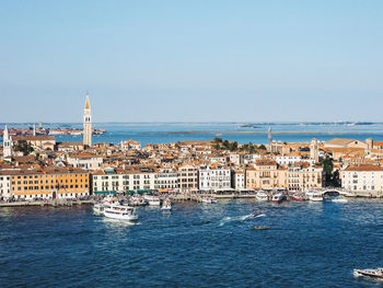 Aerial view of buildings by sea against clear sky during sunny day