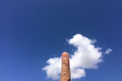 Low angle view of human hand against blue sky