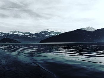 Scenic view of sea by snowcapped mountains against sky