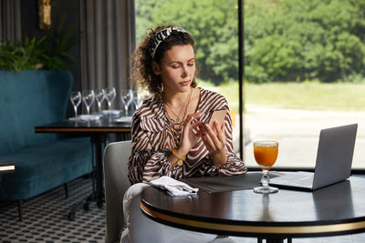 Young woman looking away while sitting on table