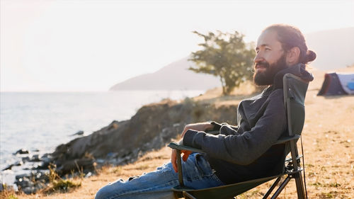 Side view of young man sitting on beach