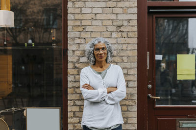 Portrait of young woman standing against wall