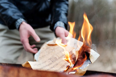 Midsection of man burning paper musical notes