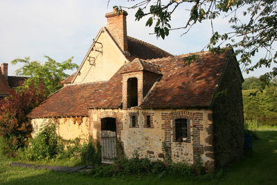 Exterior of old house on field against sky
