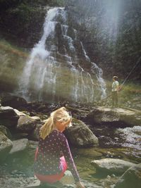 Full length of young woman standing on rock by river