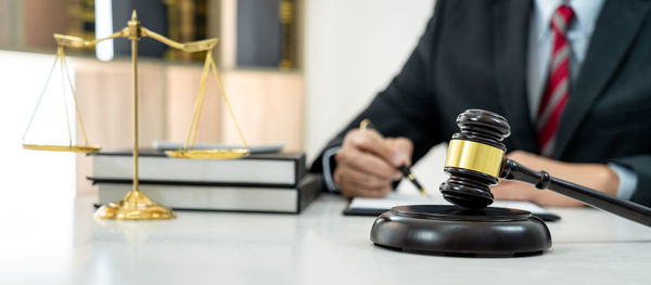 Midsection of lawyer holding trophy on table