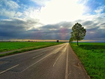 Road amidst field against sky