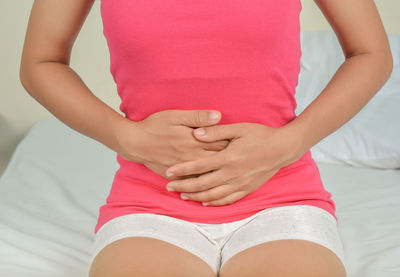 Midsection of woman touching bed