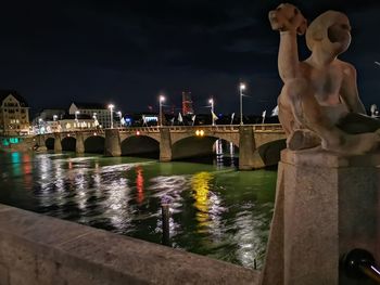 Statue of illuminated bridge over river against sky at night