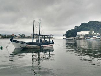 Boats in harbor against cloudy sky