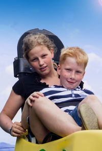 Portrait of mother and son sitting on toboggan slide against sky