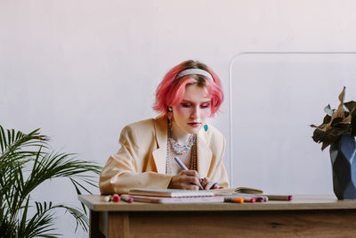 Portrait of young woman using mobile phone while sitting on table