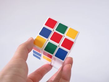 Close-up of hand holding toy over white background