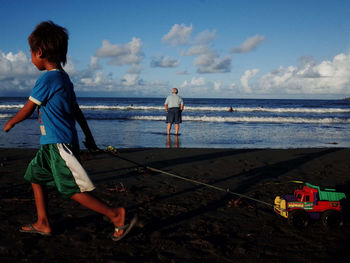 Men standing on beach against sky