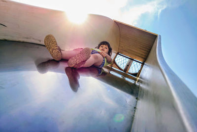 Low angle view of cute girl on slide against sky