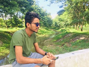 Young man sitting on retaining wall at park