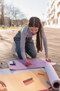 Young woman writing on banner outdoors