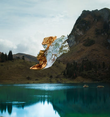 Foil flying over lake by mountain