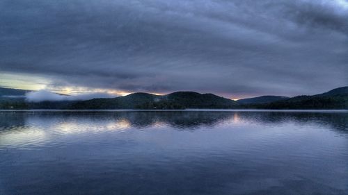 Scenic view of lake and mountains against cloudy sky