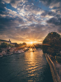 View of canal along trees at sunset