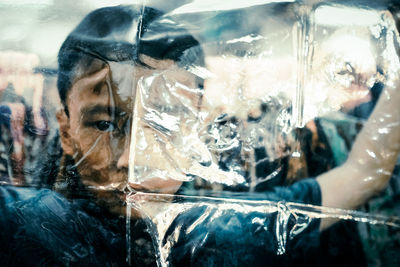 Close-up portrait of woman with reflection in glass