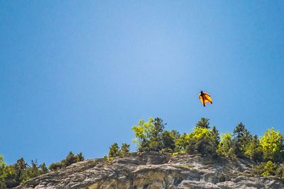 Low angle view of person paragliding against clear blue sky