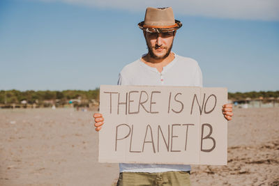 Man standing by text on land against sky