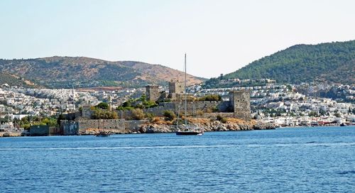 Scenic view of sea by cityscape against clear sky