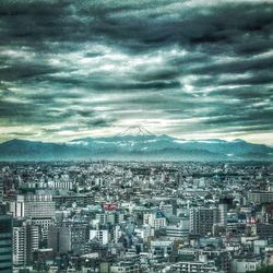 Aerial view of cityscape against cloudy sky