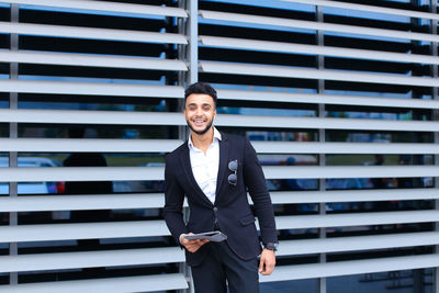 Portrait of smiling businessman holding digital tablet