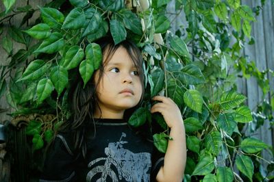 Cute boy looking away against plants