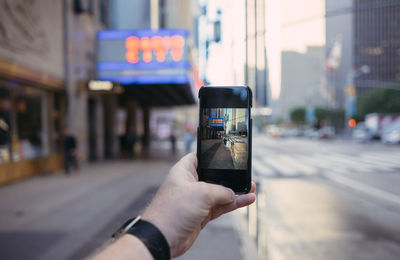 Close-up of hand using mobile phone in city