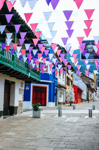 Multi colored umbrellas hanging over street amidst buildings in city