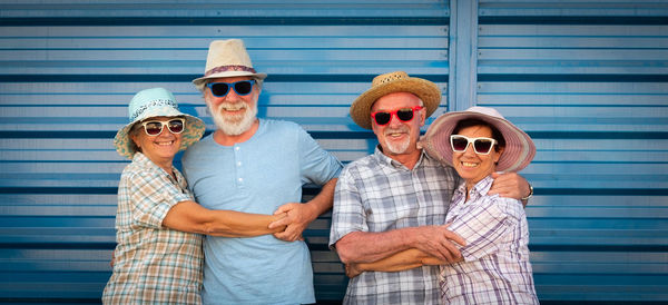 Portrait of smiling senior couples standing with arms around against shutter