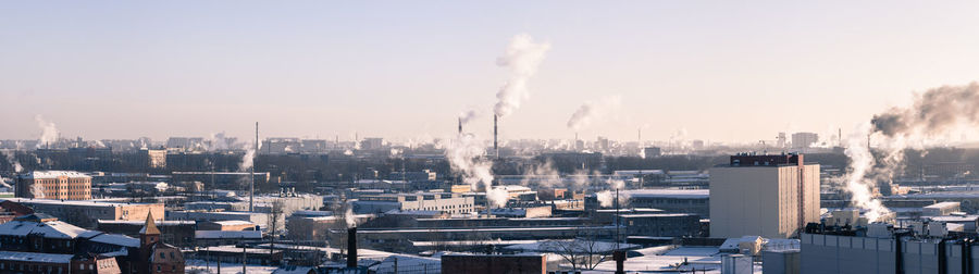 Smoke emitting from factory against sky in city