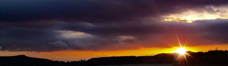 Scenic view of mountains against cloudy sky at sunset