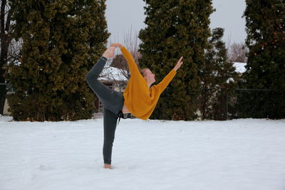 Woman jumping on snow covered trees