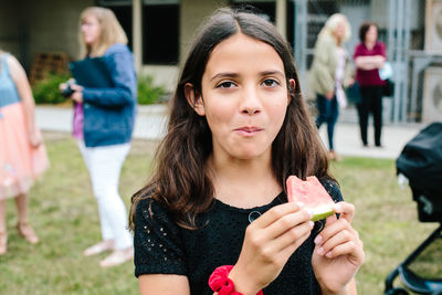 Girl looks at camera after taking a bite of watermelon