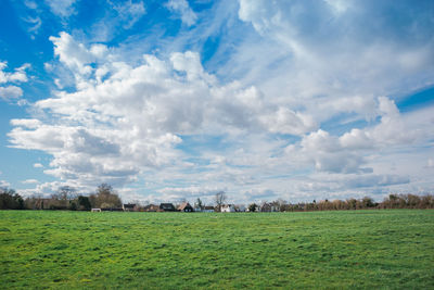 Scenic view of grassy field against cloudy sky