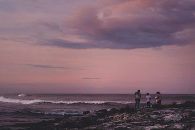 People on beach against sky during sunset