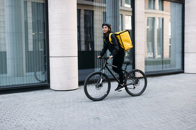 Man riding bicycle on street against building