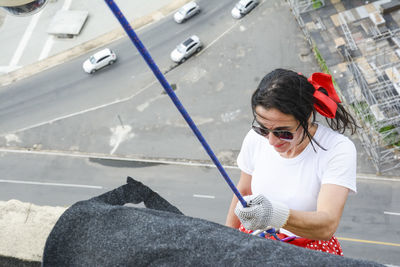 Caucasian woman wearing hero costume descending a tall building in rappel. 