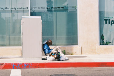 Full length of man sitting on road in city